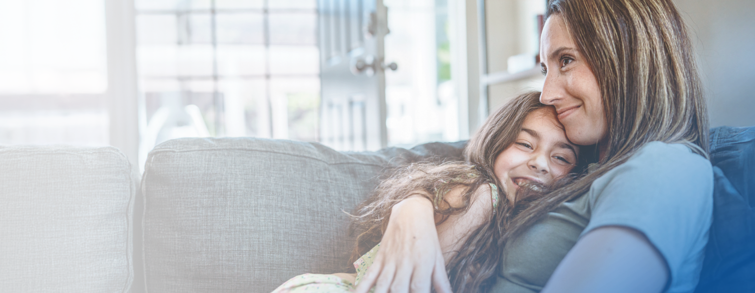 a woman hugging a young girl on a sofa